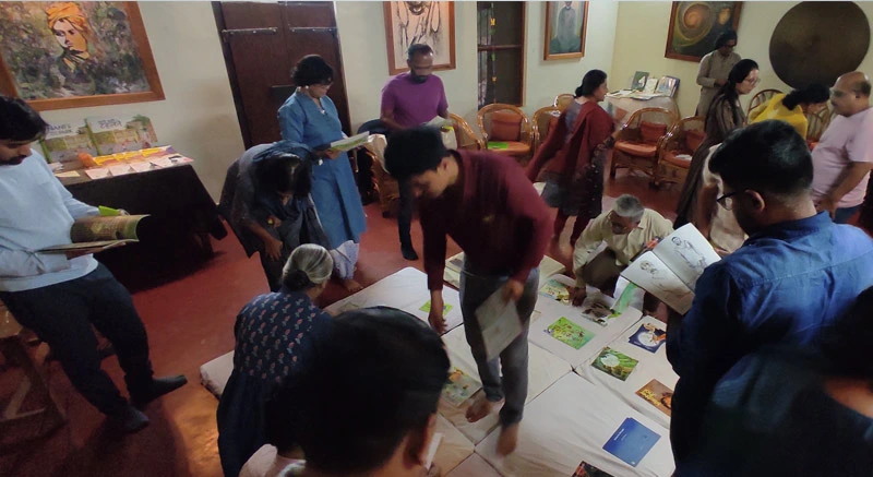 Participants exploring a curated collection of books laid out at the Bimba Pratibimba workshop, to select the books they wish to translate as an outcome of the workshop