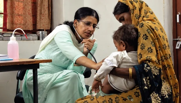 Healthcare worker examining a young child with their mother