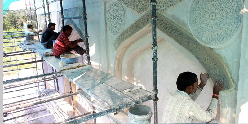 Craftsmen restoring intricate lime stucco patterns on the Tomb of Sultan Quli Qutb-ul-Mulk